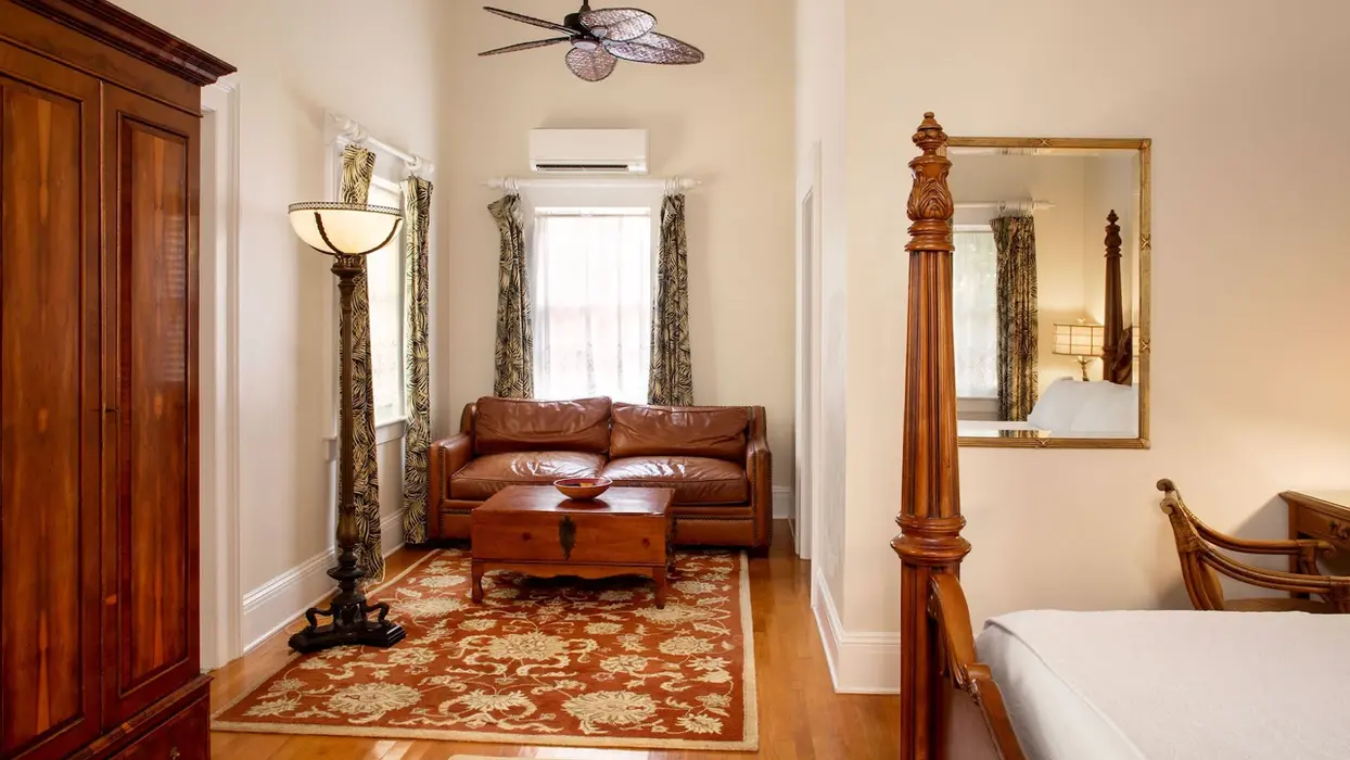 Cozy cottage bedroom with leather sofa and four-poster bed