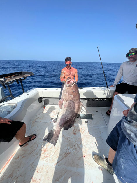 Man on fishing boat holding a large fish