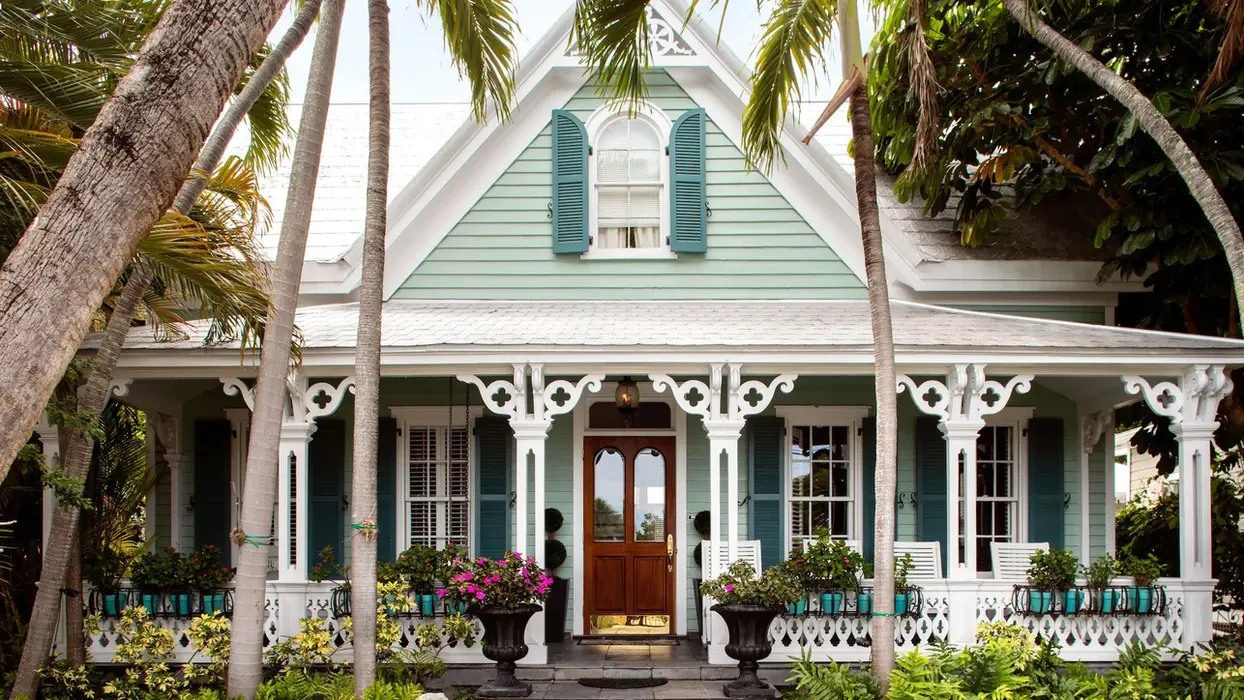 Tropical cottage with a white porch and palm trees