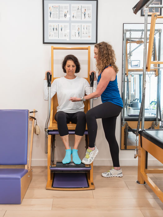 Instructor assisting woman on Pilates Wunda Chair