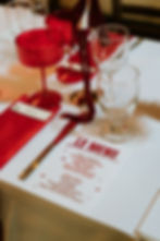 Menu de mariage Chris & Noe sur table avec verres rouges.