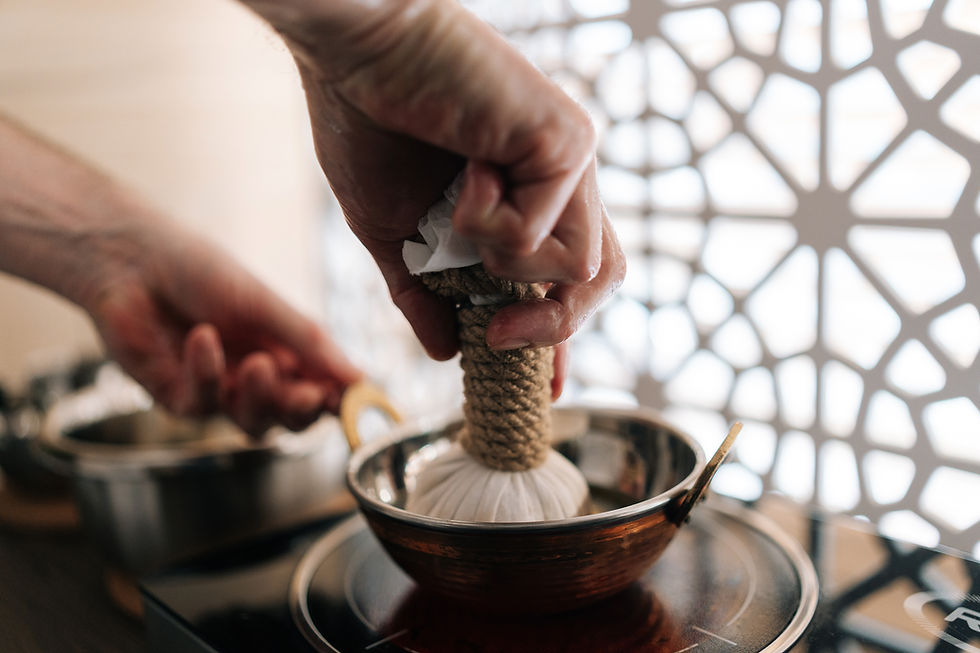 Closeup of ayurvedic massage practitioner male dipping cotton-wrapped herbal bundle into a