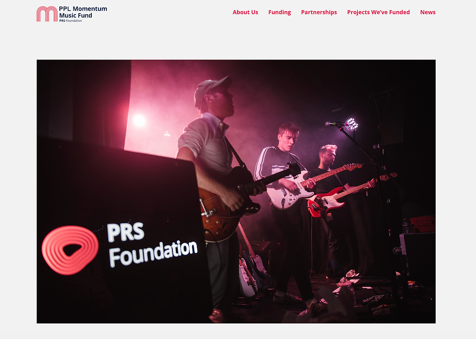 Three musicians perform with guitars on a dimly lit stage, with the PRS Foundation logo on a sign. The mood is energetic.