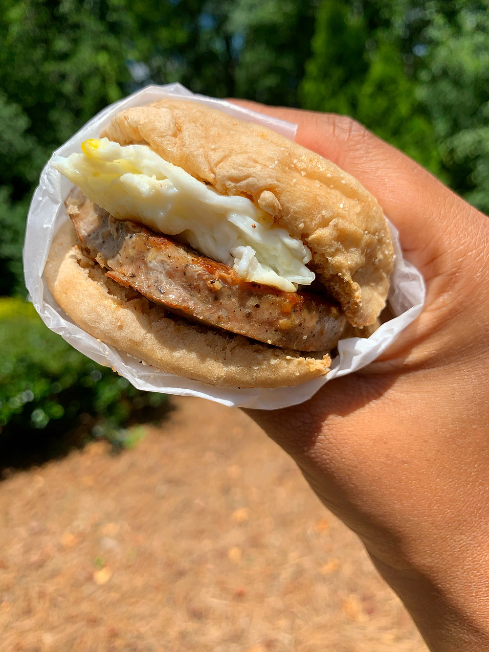 hand holding a sausage egg and cheese sandwich on english muffin