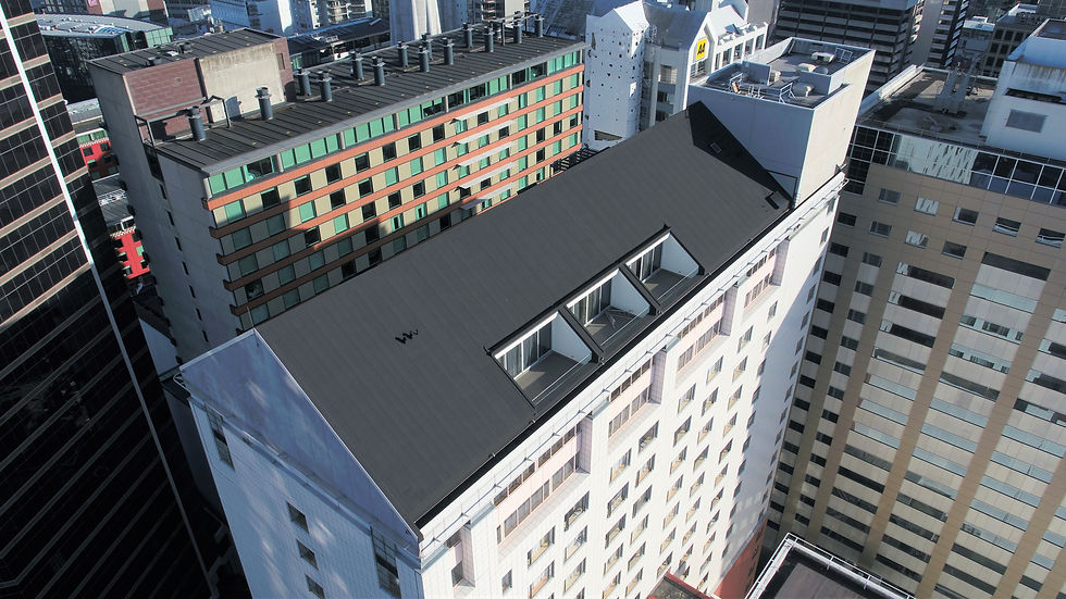 High-angle view of a roof renewal project on a city building, featuring a sleek black roof with skylights surrounded by urban structures.