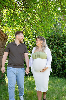 Lorena mit Babybauch und Kevin Hand in Hand im Grünen  