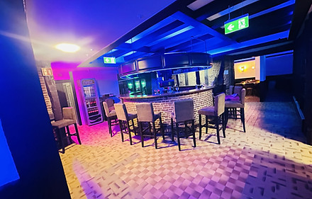 Bar mit blauer Beleuchtung und Hockern