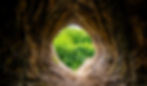 Wide angle view from a limestone cave into the green countryside with fresh foliage The “G