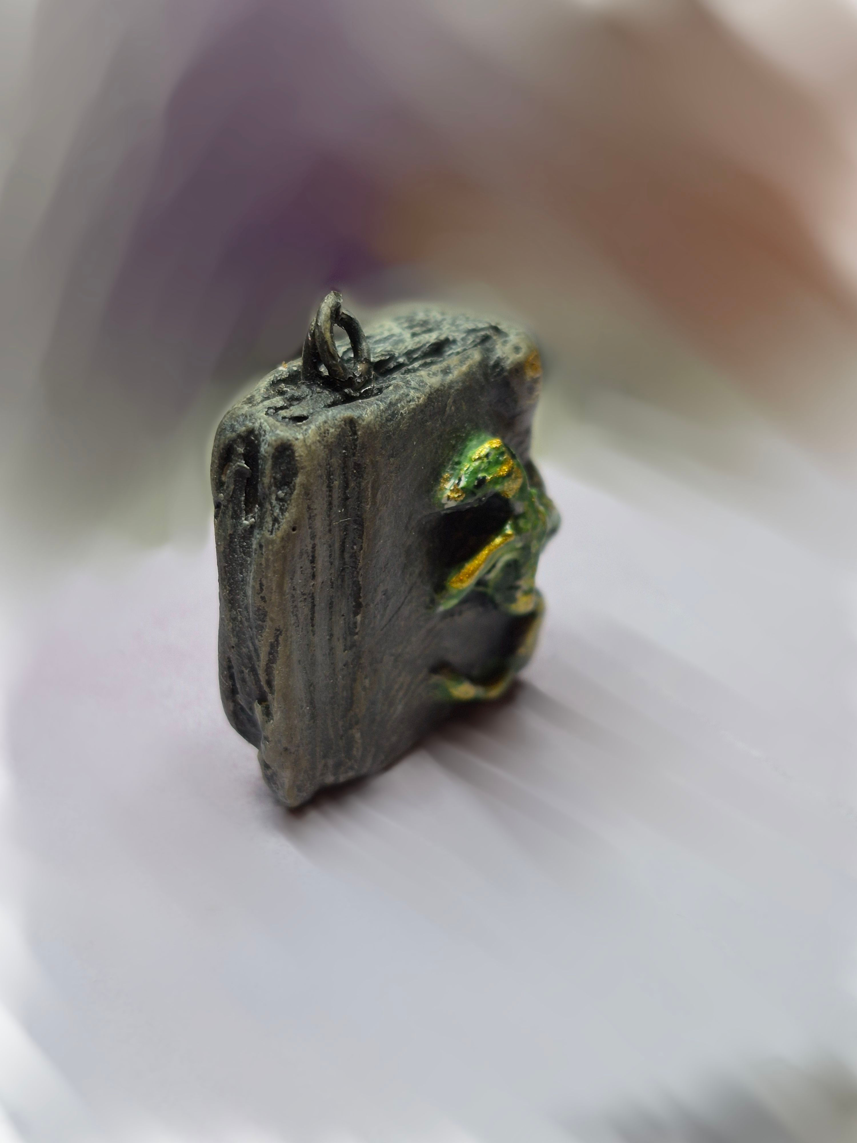 Side view of hand-sculpted ceramic miniature book showing its tiny scale and dimensional dragon detail