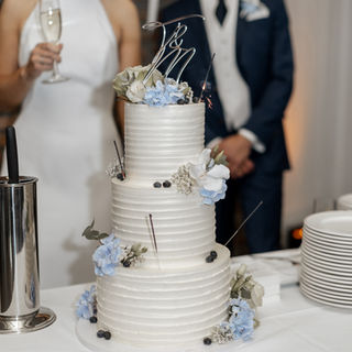 Weiße Hochzeitstorte mit blauen Blüten und schlichter Struktur-Optik