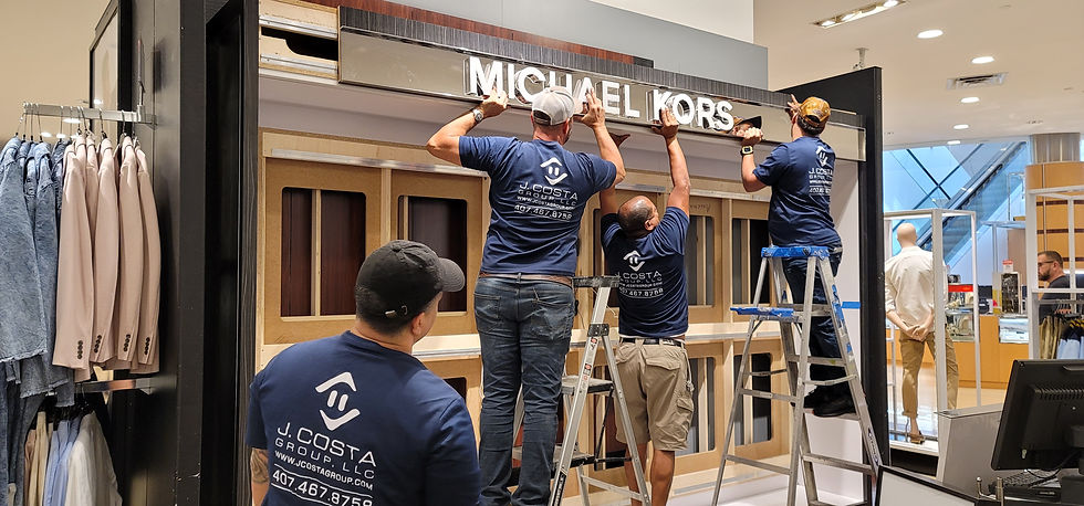 Some of the team at J.Costa Group installing a Michael Kors display sign