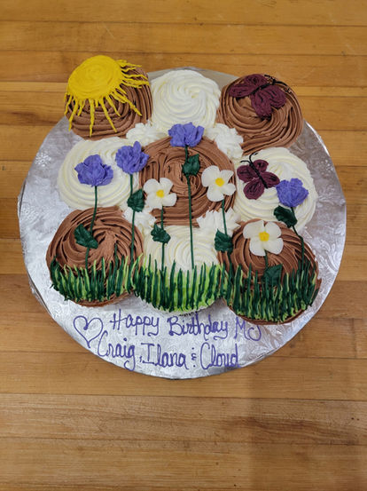 Decorated cupcakes arranged on a silver platter with "Happy Birthday Craig Ilana & Cloud"