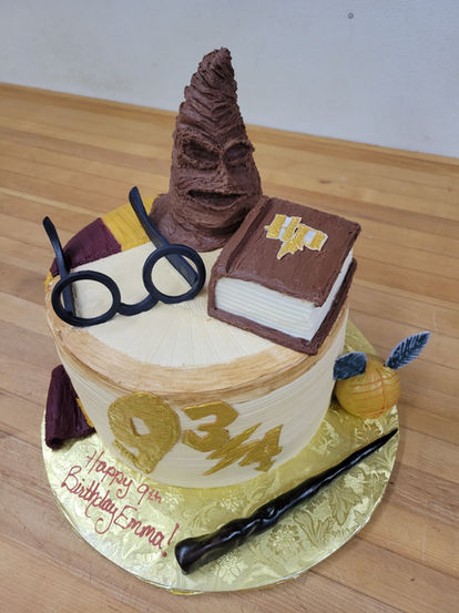 Harry Potter birthday cake with wand, book, glasses, and Sorting Hat.