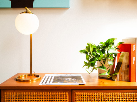 Golden lamp, books, and a plant sit on a wooden cabinet's surface.