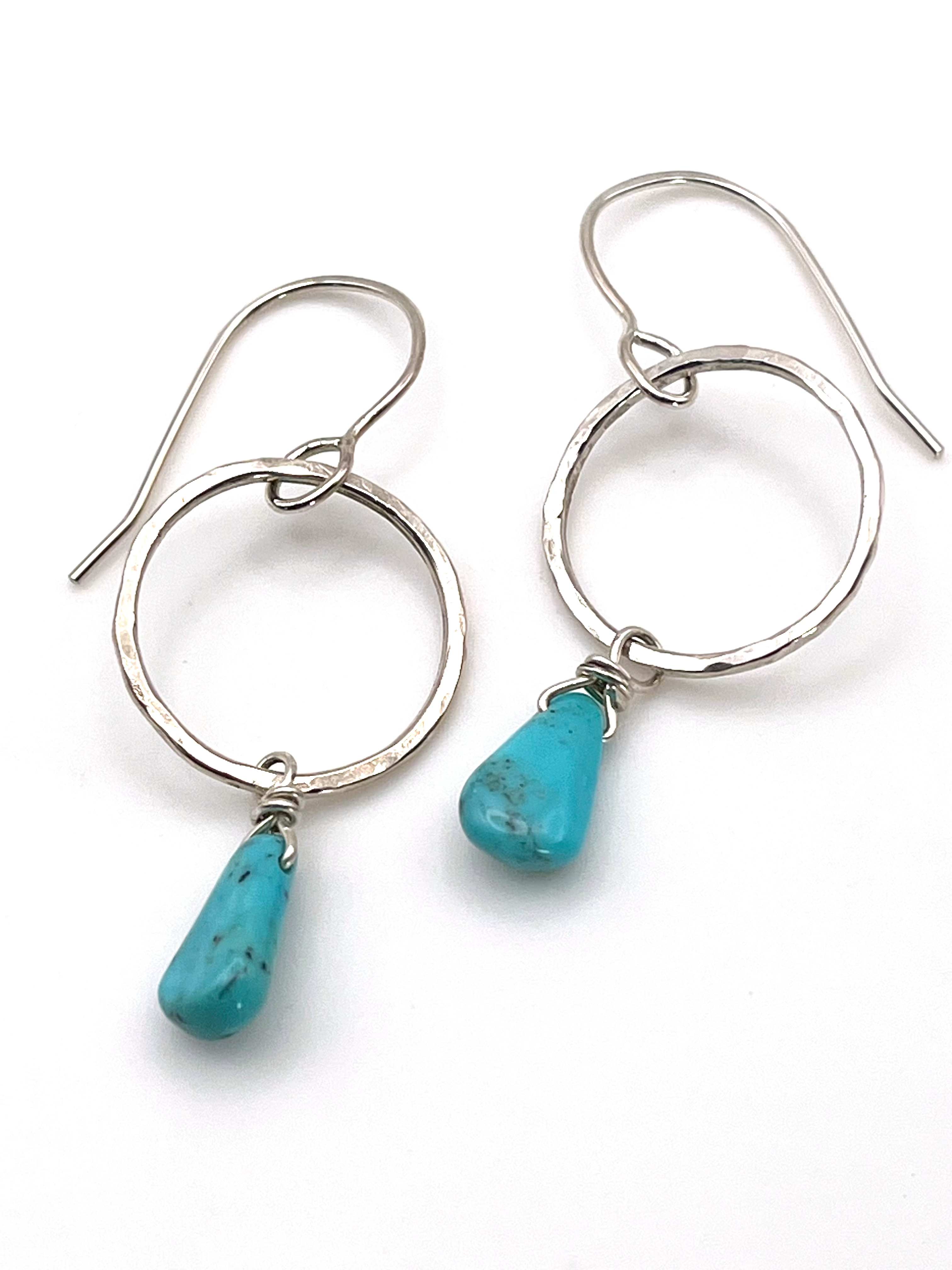 sterling silver circle earrings with turquoise drop on flat white surface