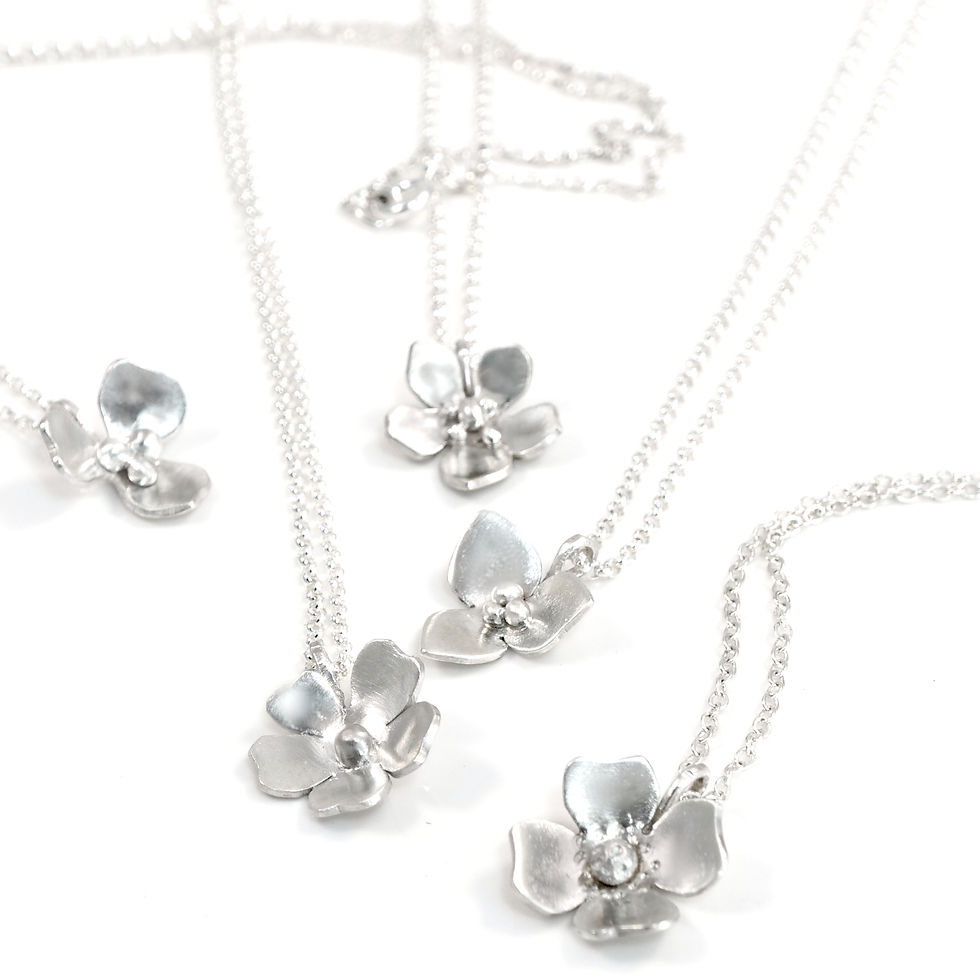 group of sterling silver bloomlette flower blossom necklaces on a white background