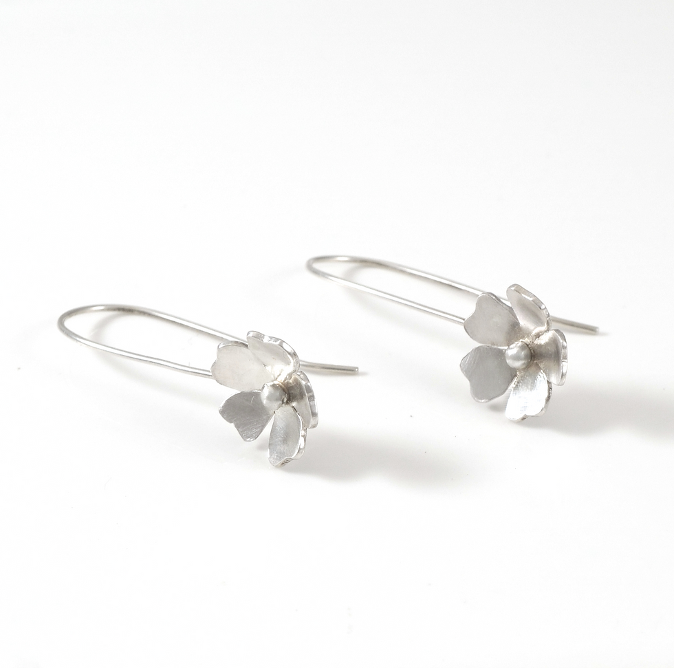 wild rose flower long sterling silver earrings laying sideways on white background