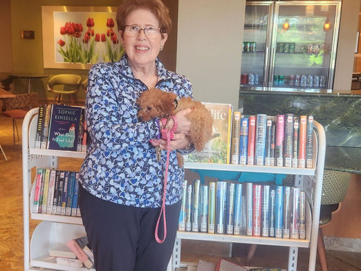 An RHPL Lobby stop patron stands in front of carts of books, holding a small dog.