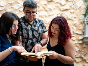 Three adults reading and discussing a book together
