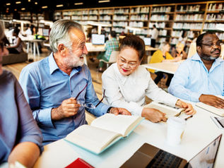 A group of adults with open books, smiling and talking with each other.