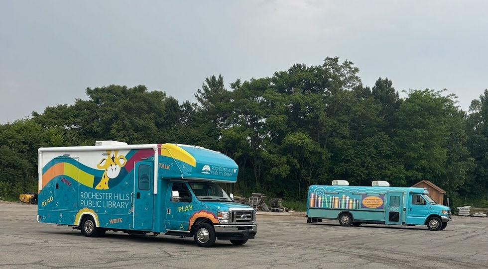 The new and old early literacy buses; the new bus is parked in the foreground, and the old in the background.