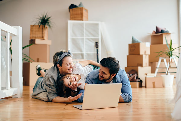 cheerful-family-using-laptop-while-relaxing-on-the-floor-at-their-new-home.jpg