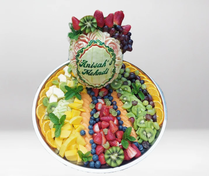 a tray of fruit with a watermelon carving that says anisah 's mehndi