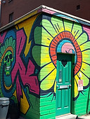 Create an image of a bright bold mural on a small building and on the right side of the ph