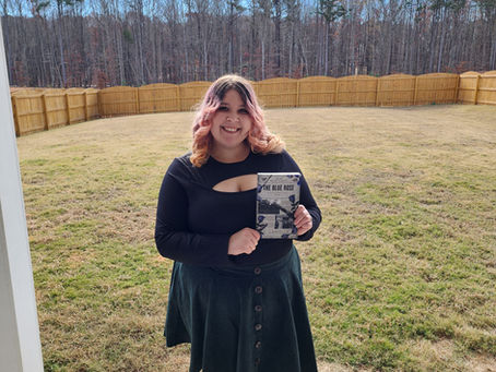 Author K. Cardella in a backyard holding her book, "The Black Lotus."