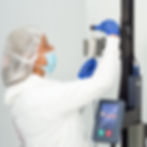 An operator is loading an in-process catheter shaft, ready for laminating, onto a vertical reflow machine