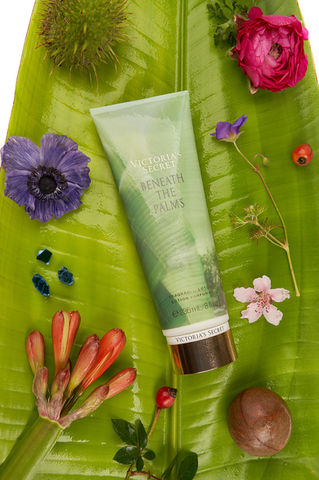 Victoria's Secret Beneath the Palms lotion flat lay with tropical flowers and palm leaves by Los Angeles beauty product photographer