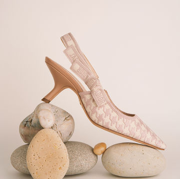 Pink Dior slingback pump with textured fabric and bow displayed on stacked pebbles in a neutral studio setup