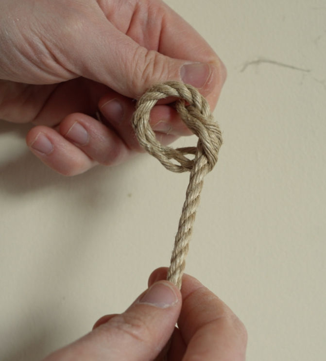 An overhand knot being tied by creating a loop in the rope.