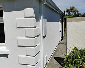 Coin stones on the corner of a house with white acrylic render finish
