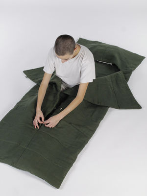 Person in green sleeping bag adjusting zipper on white background, top view