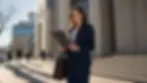 Female attorney reviewing a legal brief on a granite courthouse plaza in Salt Lake City, afternoon light