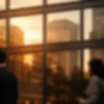 Reflections of sunset and buildings on glass windows, with two blurred people in the foreground. Warm hues create a serene mood.