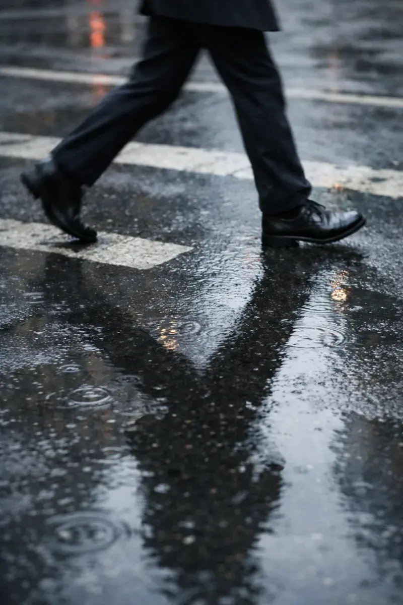 Person’s shoes and shadow on wet asphalt as they walk with purpose toward a felony defense attorney meeting.