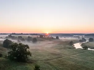 Fog lifting over a valley at sunrise with open sky space, setting a calm hero banner about getting legal help.
