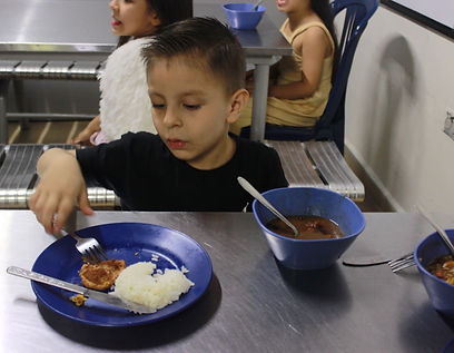 Niño beneficiario de la Fundación CAESPRO disfrutando de un almuerzo nutritivo en el comedor escolar, como parte del programa