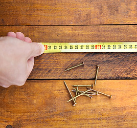 male-hand-measuring-wooden-floor-PW9NQUS