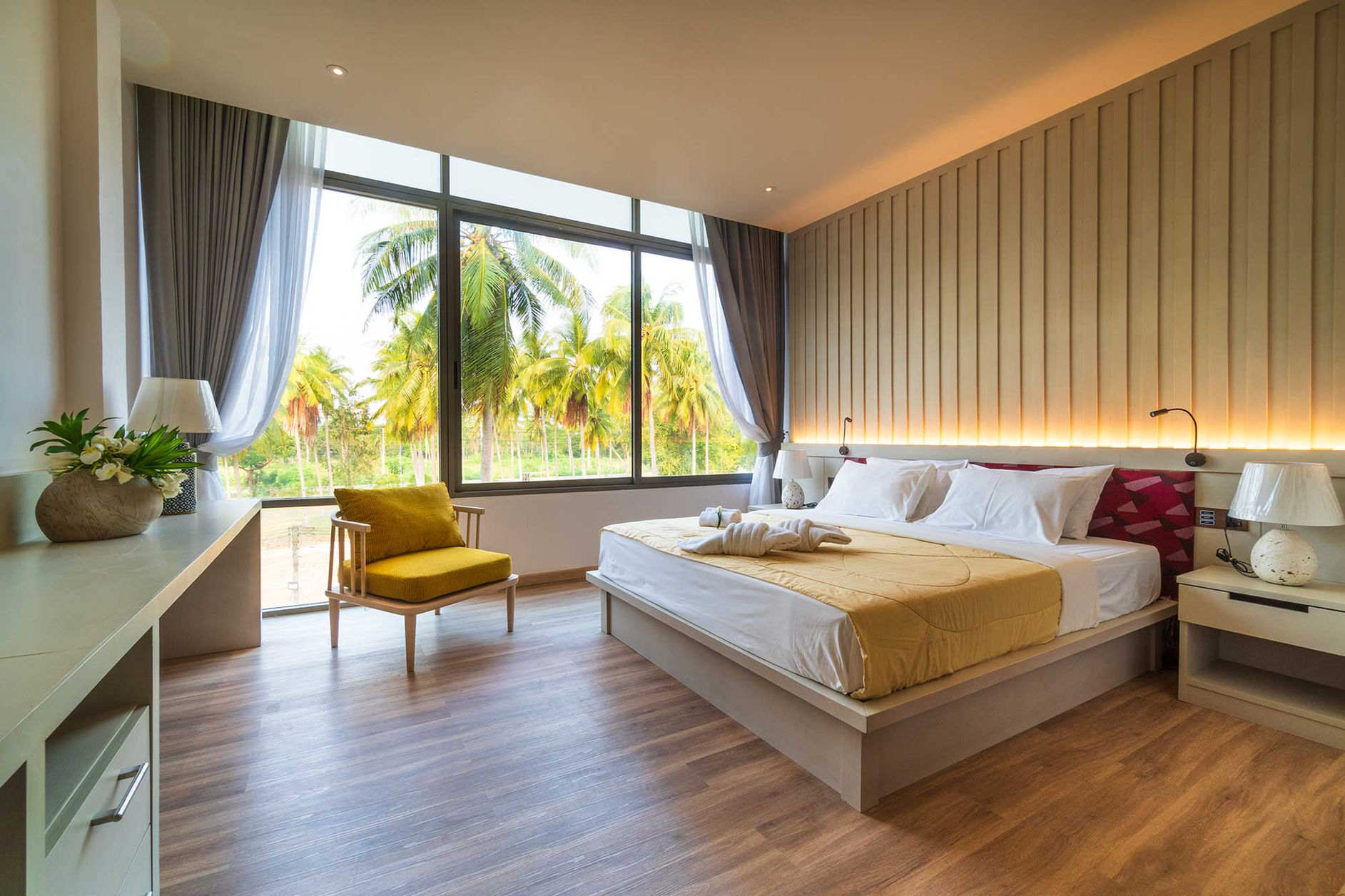 ห้องนอนทันสมัยมีเตียง เก้าอี้ และวิวต้นปาล์ม