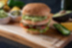 Cooked shrimp burger with lettuce, tomato, and guacamole on a toasted bun