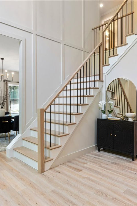 An image of a foyer white and oak staircase with detailed molding on the walls. Designed and built by Evolution General Contracting.