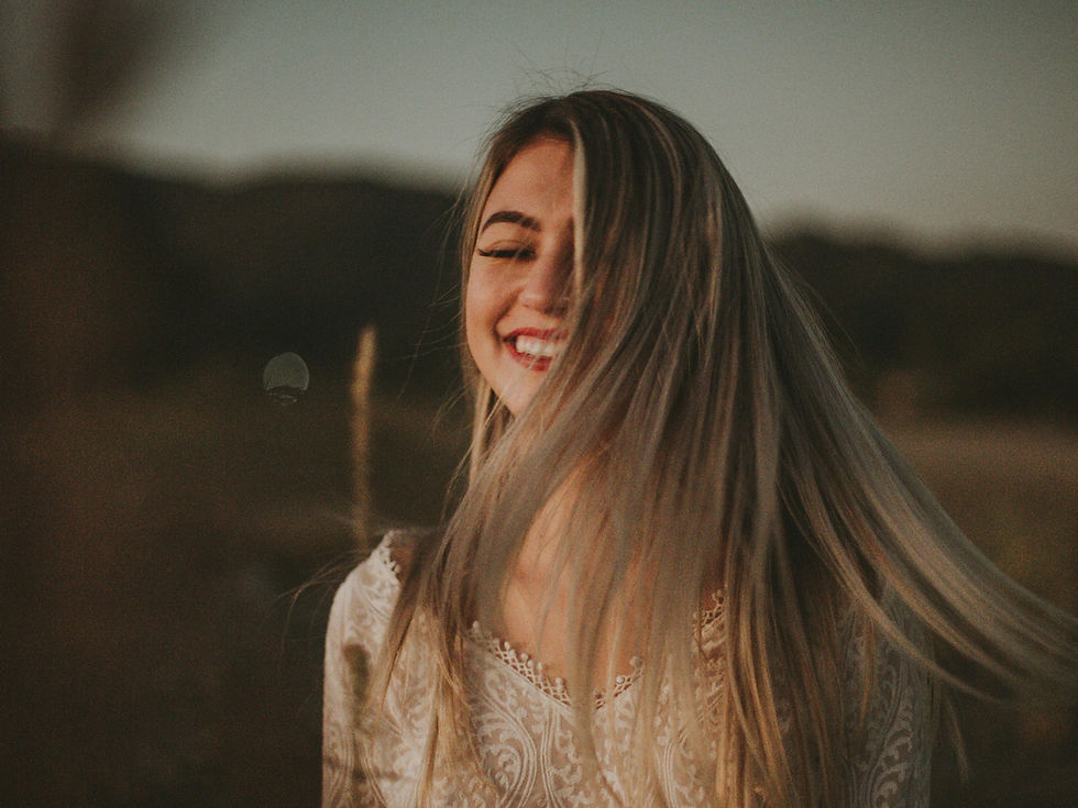 Woman smiling joyfully outdoors in nature, representing freedom from emetophobia after hypnotherapy