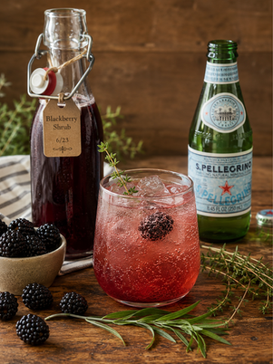 a glass of blackberry herb shrub with sparkline water