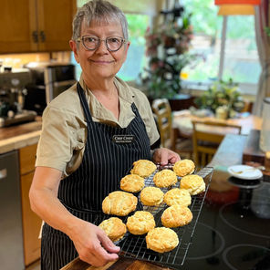 author holding a cooling rack of vegan buttermilk biscuits out of the oven