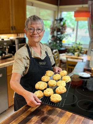 author holding a cooling rack of vegan buttermilk biscuits out of the oven