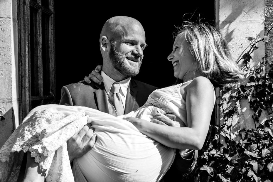 Bride carried over the threshold - Riverside castle wedding venue in ancient parkland in central France.