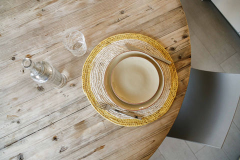 An aerial view of a partial round wooden table and a cup of coffee on a saucer
